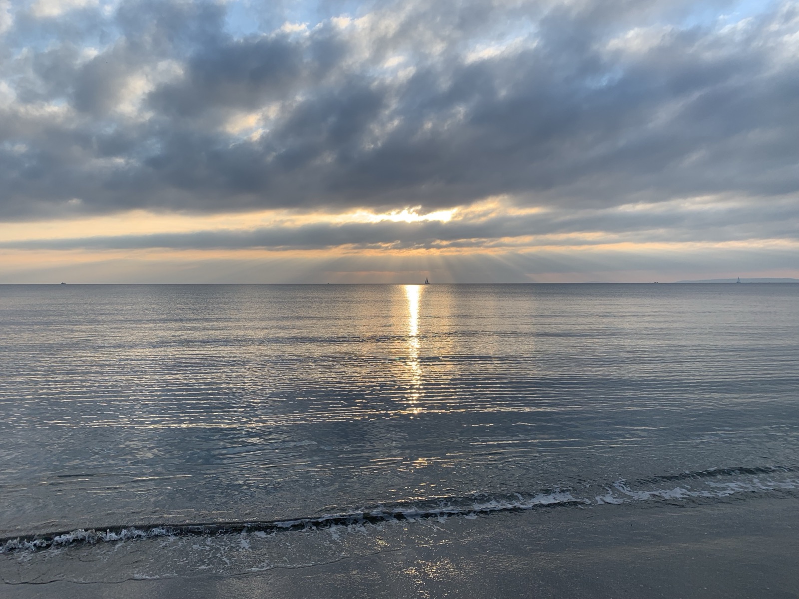 Sun breaking through clouds over a calm sea